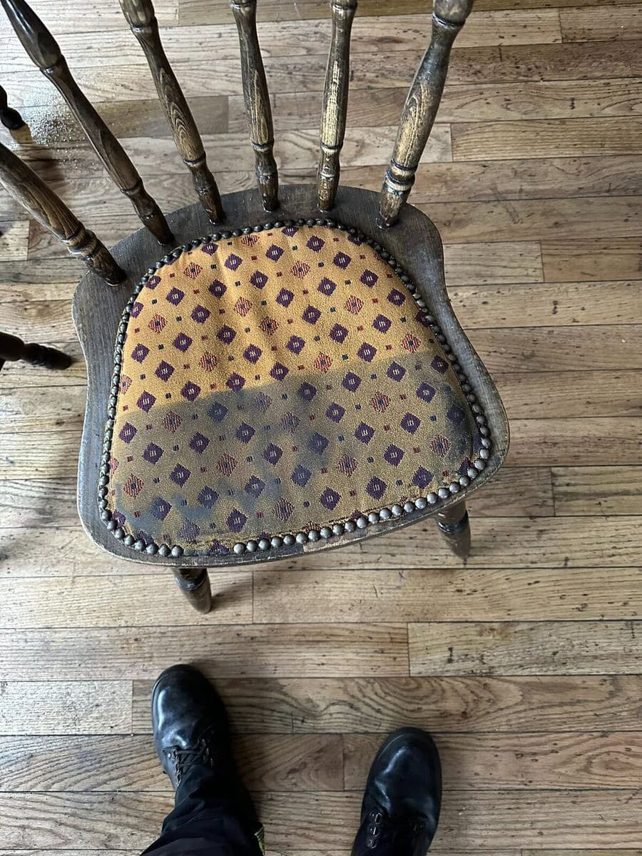 Fabric-covered dining stool — a padded seat on a frame being cleaned